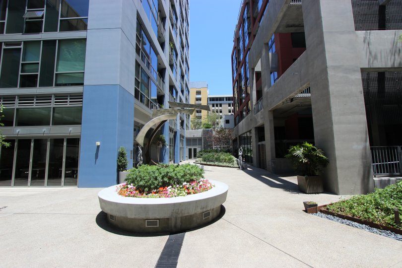 The exterior of the Icon building showing the entrance doors, blue building, and open portico with potted plants on a sunny day.