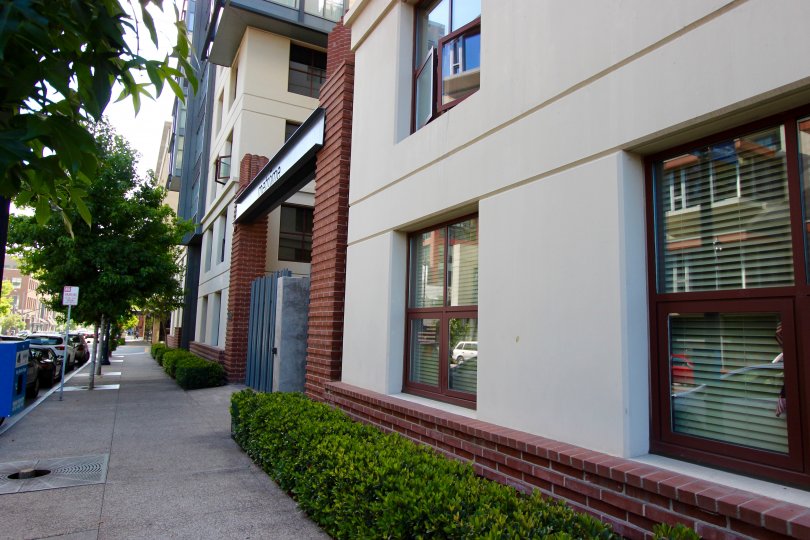 A sunny day in the area of Metrome, outside, sidewalk, fence, trees, windows, condo