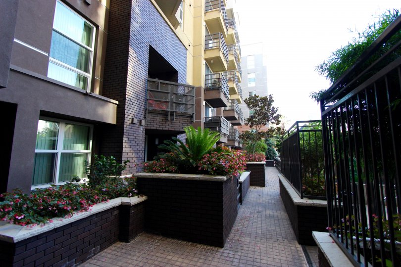 Brick road lined with flower planters and a black iron fence at Park Blvd East in Downtown San Diego CA