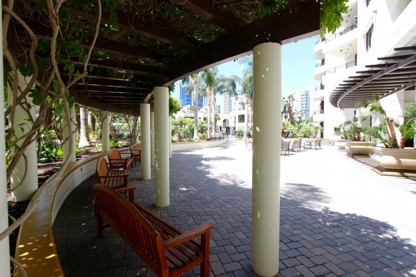 A shaded corridor bordering a park next to a residential building.