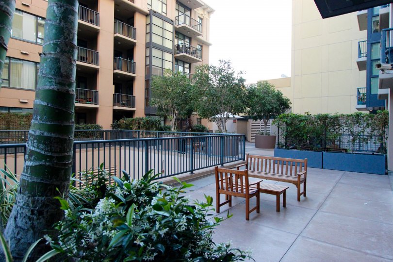 A sunny day in the area of Trellis, outside, fence, table, chair, bench, tree, balcony