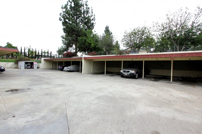 A cloudy day overlooking garage with parked cars and trees.