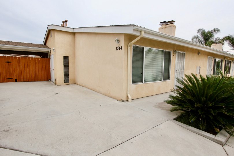 A one-level older yellow house with brown fencing in Cuyamaca neighborhood of El Cajon, CA