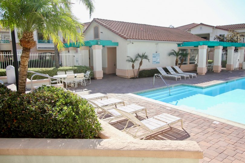 VERY BEAUTIFUL HOUSE. IN FRONT OF IT THERE ARE FOUR SMALL TREES. AND THERE IS A ROAD, VERY CLEAN. AND THERE IS A POOL.