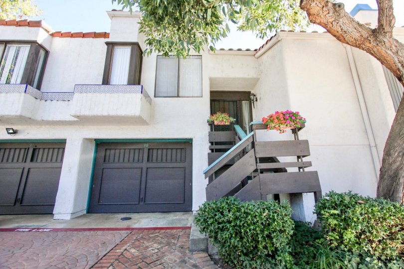 Attached townhouse with single car garage, decorative wooden railings and mature tree with stucco exterior at Sunset Woods