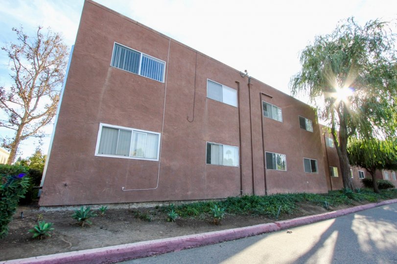 Reddish building surface on the side of the road with multiple windows, located in Villa La Paz, in Escondido, California.