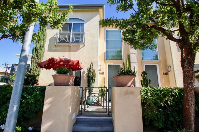 Wellington Square beige two-story with gate and trees Hillcrest California