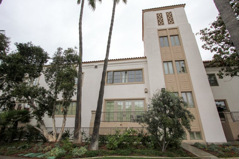 A very tall adobe building with architectural details and palm trees in La Jolla Prospect Condos