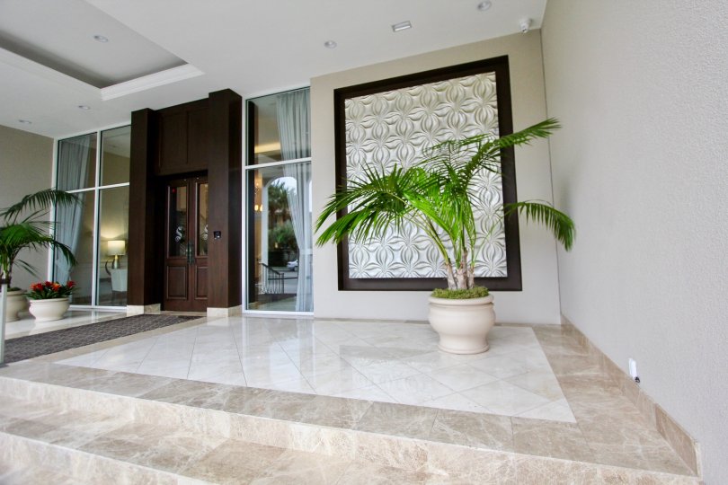 The Hall in the La Jolla Seville has flower pot on the two side of the door and with a room in front