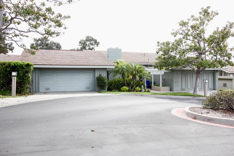 A gray one story ranch style home sits in front of a round driveway in the Mount La Jolla Community
