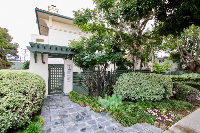 THE BUILDING IN THE PACIFIC VILLAS WITH THE TREES, PLANTS, STEEL GATE, FLOWERS, PATHWAY