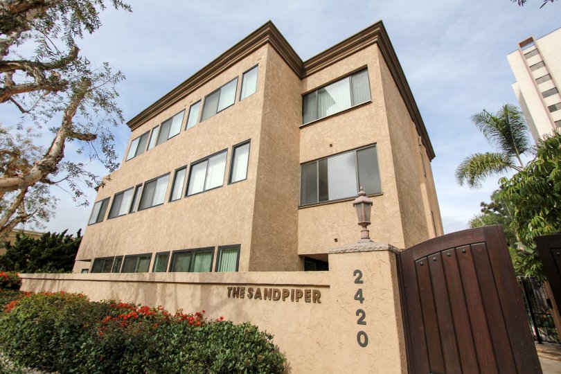 In The Sandpiper, a bush with flower in the entrance and Apartment has 3 floors