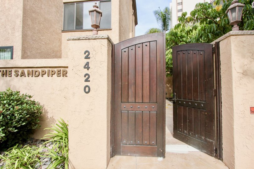 Ornate double door entrance with high privacy fences and decorative light sconces in La Jolla