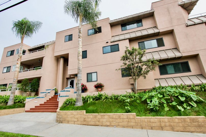 Three story pink building with grass & plants in Villa Italian community in La Jolla CA