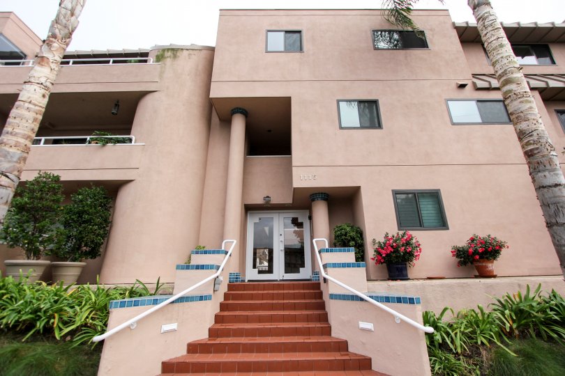 A front entrance to a building with a nicely laid out brick stairs in the Villa Italia community. The setting is in La Jolla California.
