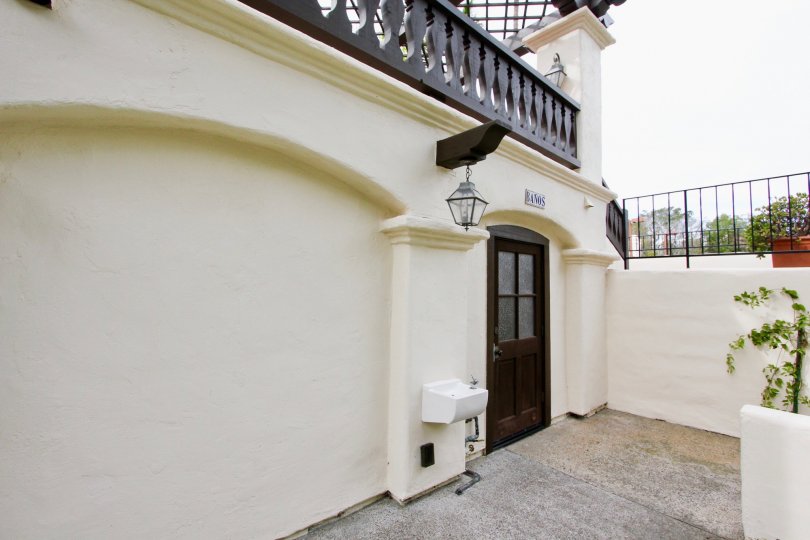 Black door next to a hanging lantern and wall at Villas Mailorca in La Jolla CA
