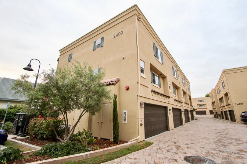 Three story brown building with garages & tiled driveway in Ziani in La Jolla CA