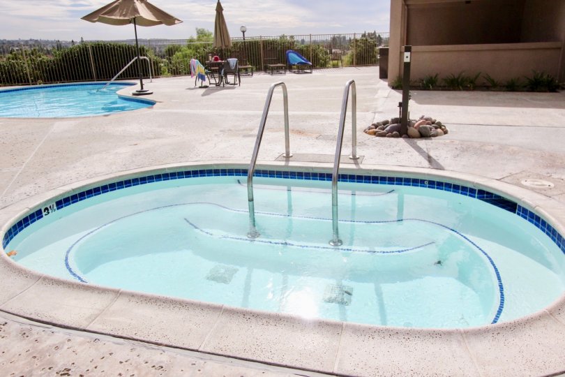 A SUNNY DAY IN THE LAKE PARK WITH THE SWIMMING POOL, UMBRELLA, TABLES, STONES