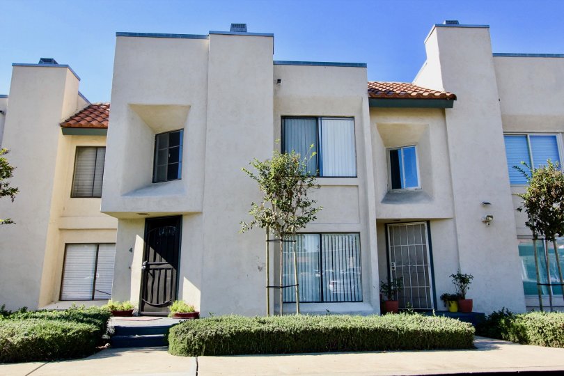 A sunny day in the Black Mountain Villas a beautiful wight color house with shrubs and small tree. a