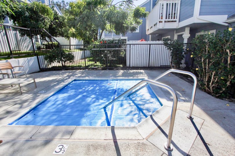 THE BUILDING IN THE CANYON COLONY WITH THE SWIMMING POOL, TABLES, ROSE PLANTS, TREES, BALCONI