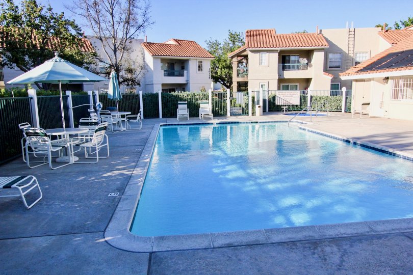 This beautiful swimming pool is located in the community of Summit Ridge, which have the lot of the chairs and tables and infront of beautiful houses, trees are there