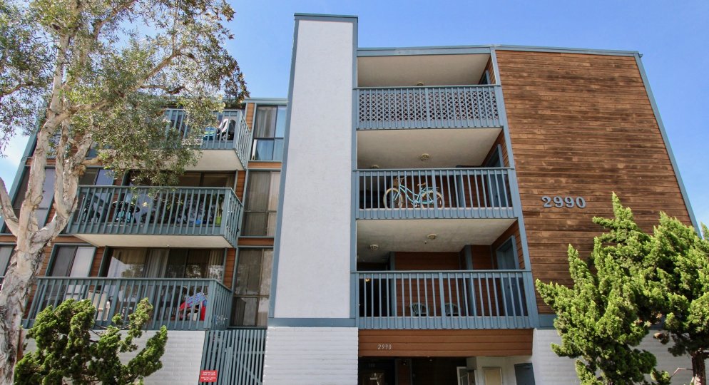 A sunny day including front view of three story apartment in 2290 Mission with trees and bycyle