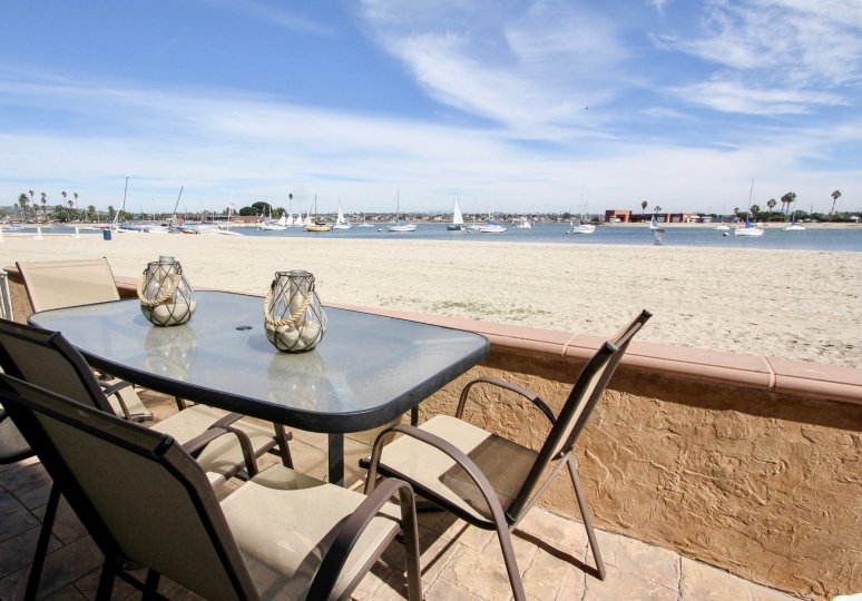 The beach and ocean view from the Carmel Villas with sand, water, and boats in a marina.