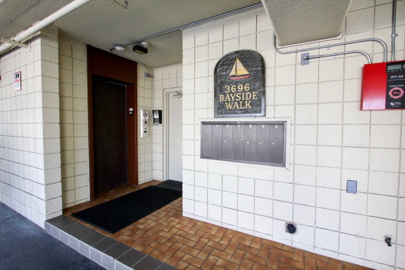The white tiled exterior of the Bayside Walk apartment complex including the resident's mailboxes.