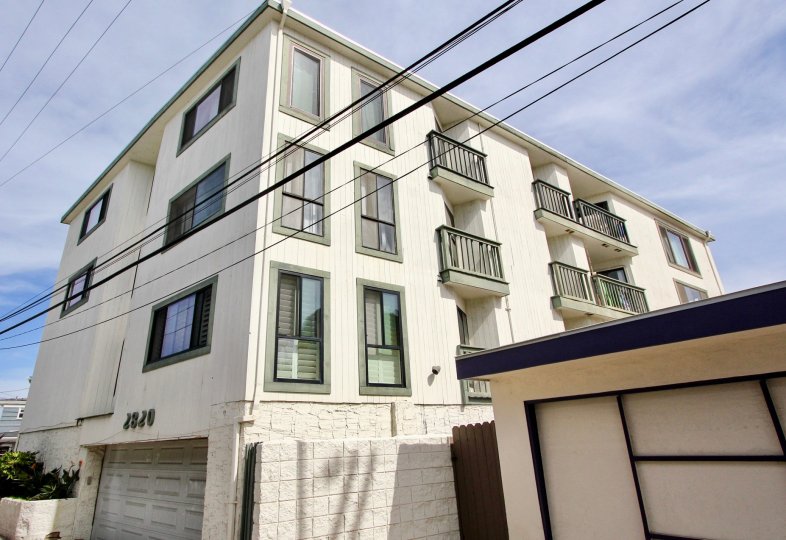 A sunny day in front of an apartment building with telephone wires in front.