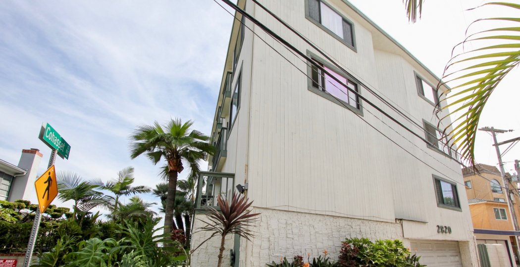 A white wood sided apartment home fronted by palm trees on Cohasset in The Fijian community.