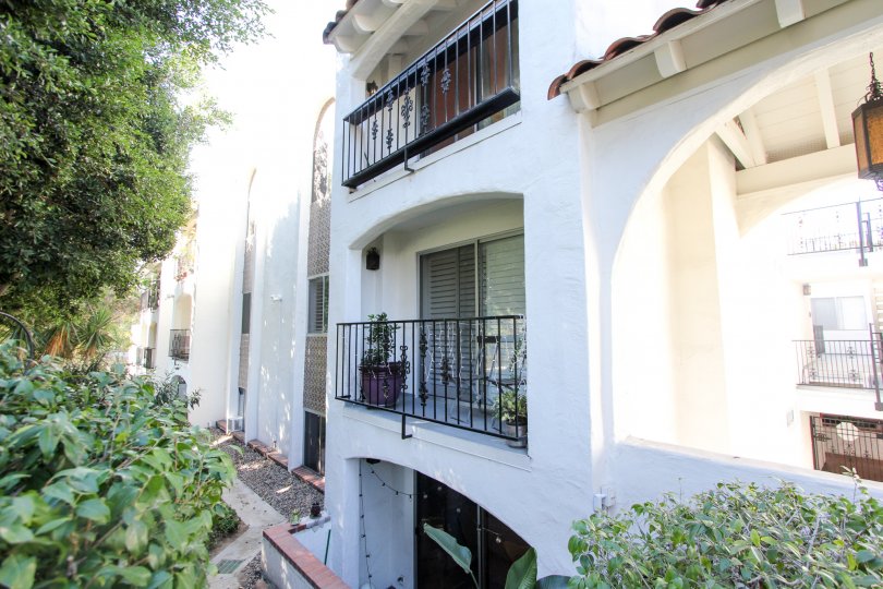 A white apartment building with some trees and bushes on the side during a sunny day in Villa Bahia, Mission Hills, CA