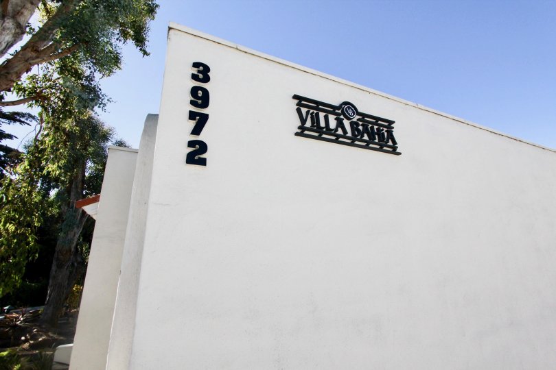 A sunny day on a tree lines street in front of Villa Bahia, with Building number showing, in Mission Hills, CA