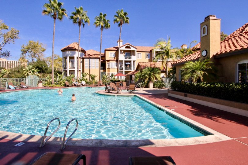 A sunny day poolside in the area of River Colony, children, palm trees, hotel, brick