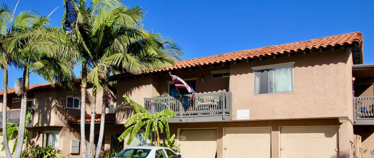 A peach colored condo with tiled roofs surrounded by palm trees in Normal Heights