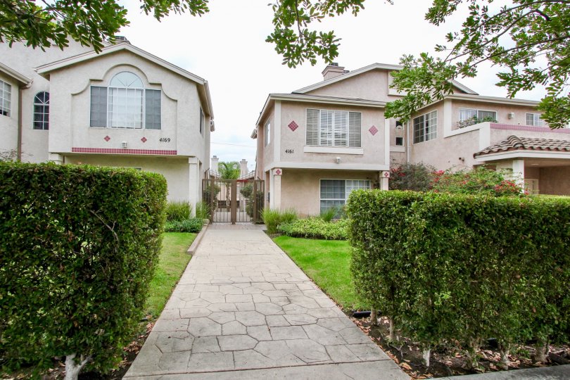 A walkway between two properties with a fence and landscaping at Mardi Gras Villas
