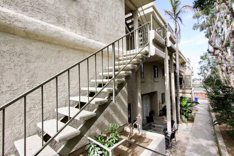 Exterior stairs and stucco exteriors with a fenced in courtyard with tall trees in Brittany Hill, Ocean Beach, CA