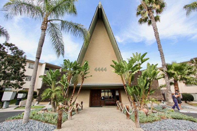 A sunny day in front of Point Loma Villas with several palm trees and bright blue skies