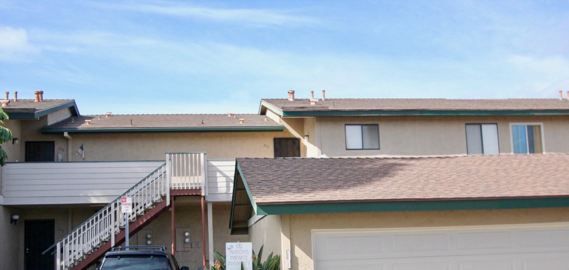 A house with red tiles with sunrays falling on the roof of the house with a black SUV parked infront at Mission vista