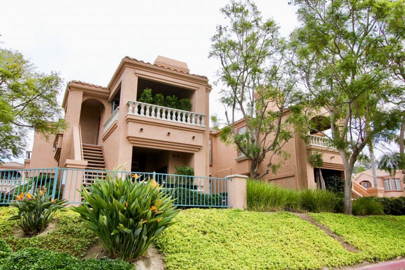 Two story pink units behind a blue fence on a hillside at Palmilla Del Oro in Oceanside CA