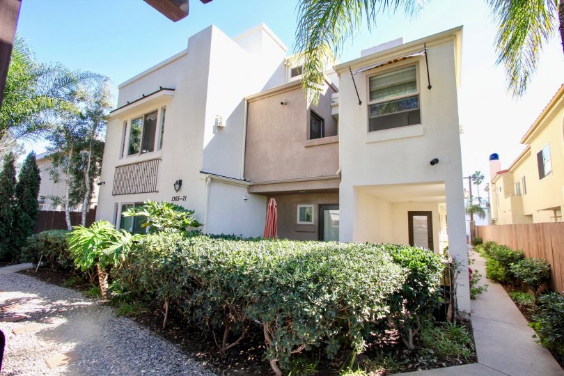 A beautiful back side of a building in the Hornblend Townhomes with some shrubs, plants and foot path.
