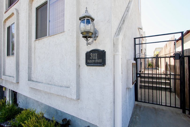 Primrose Gardens, Point Loma, California. A black gate sits adjacent to a white stone building.