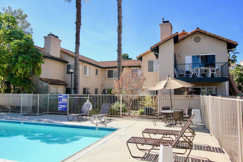 Blue swimming pool with patio chairs and fence at The Falls in Rancho Bernardo CA