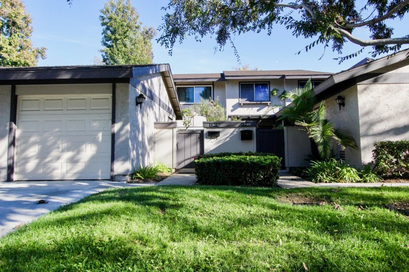 The villa's in the Westwood Townhomes has grass and bushes in front the home aside of the pathway