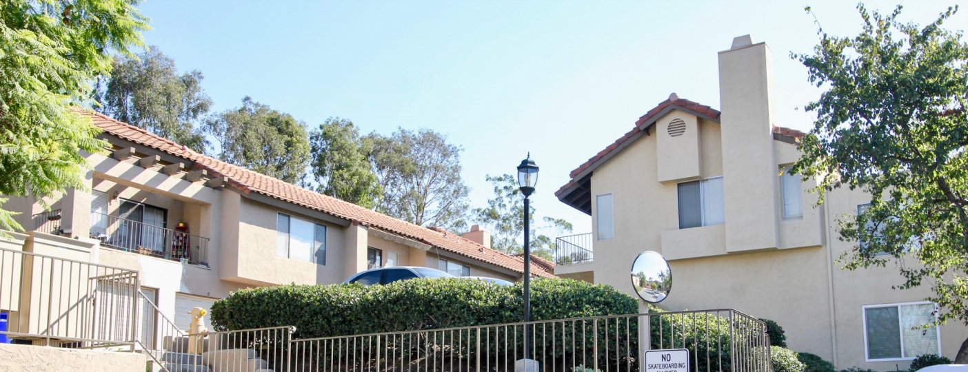 front view with bushes and fence in front and classic buildings in the back with lamp post