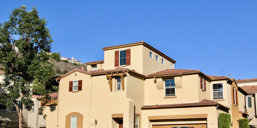 A tan Spanish style house sits near a steep hill in Springfield condos