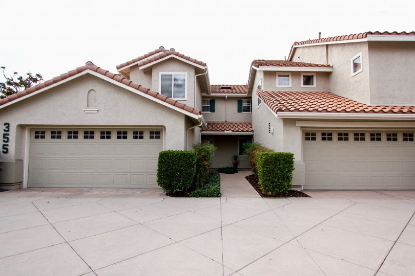 A sunny day in the area of California Mariposa, garage, bushes, window, condo, driveway