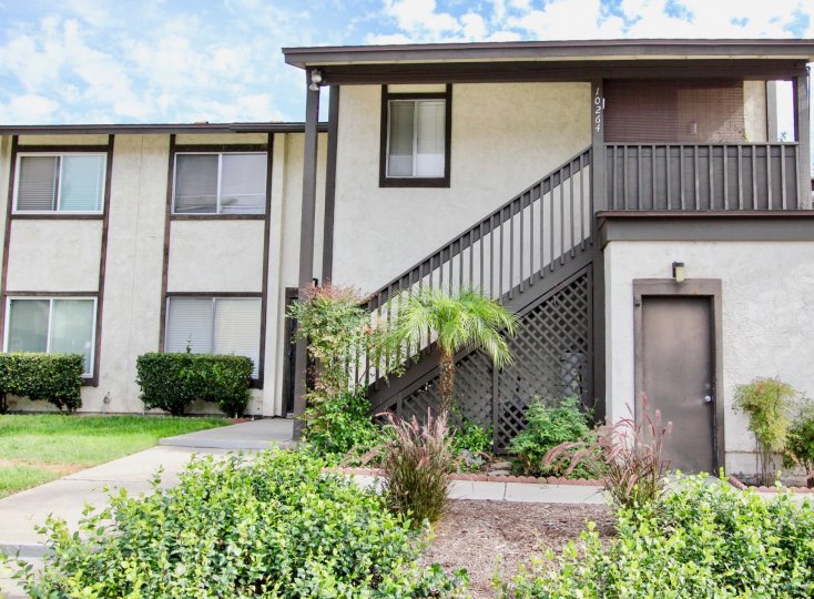 the front yard are wtih green landscaping in front of stairs leading to a second floor apartment in the Carefree East community in Santee, California