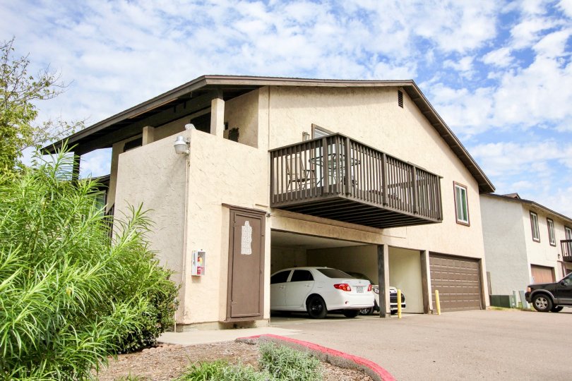 Carefree East, Santee, CA.  A large brown houe with a 3 car garage, full deck, columns, and green landscaping.