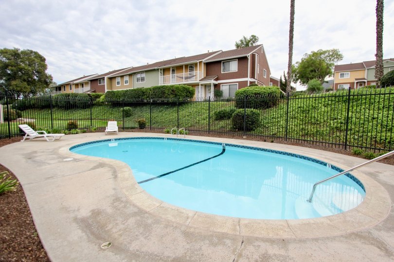 A pool with a concrete patio and lawn chairs for sitting in Pepperhill Townhomes