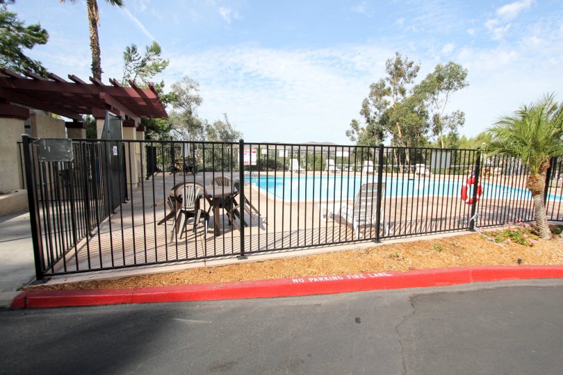 A sunny day poolside in the area of Riderwood Terrace, bouy, table, chairs, fence